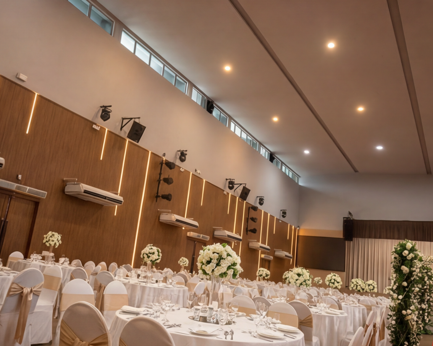High ceiling hall view with wall lighting and event tables